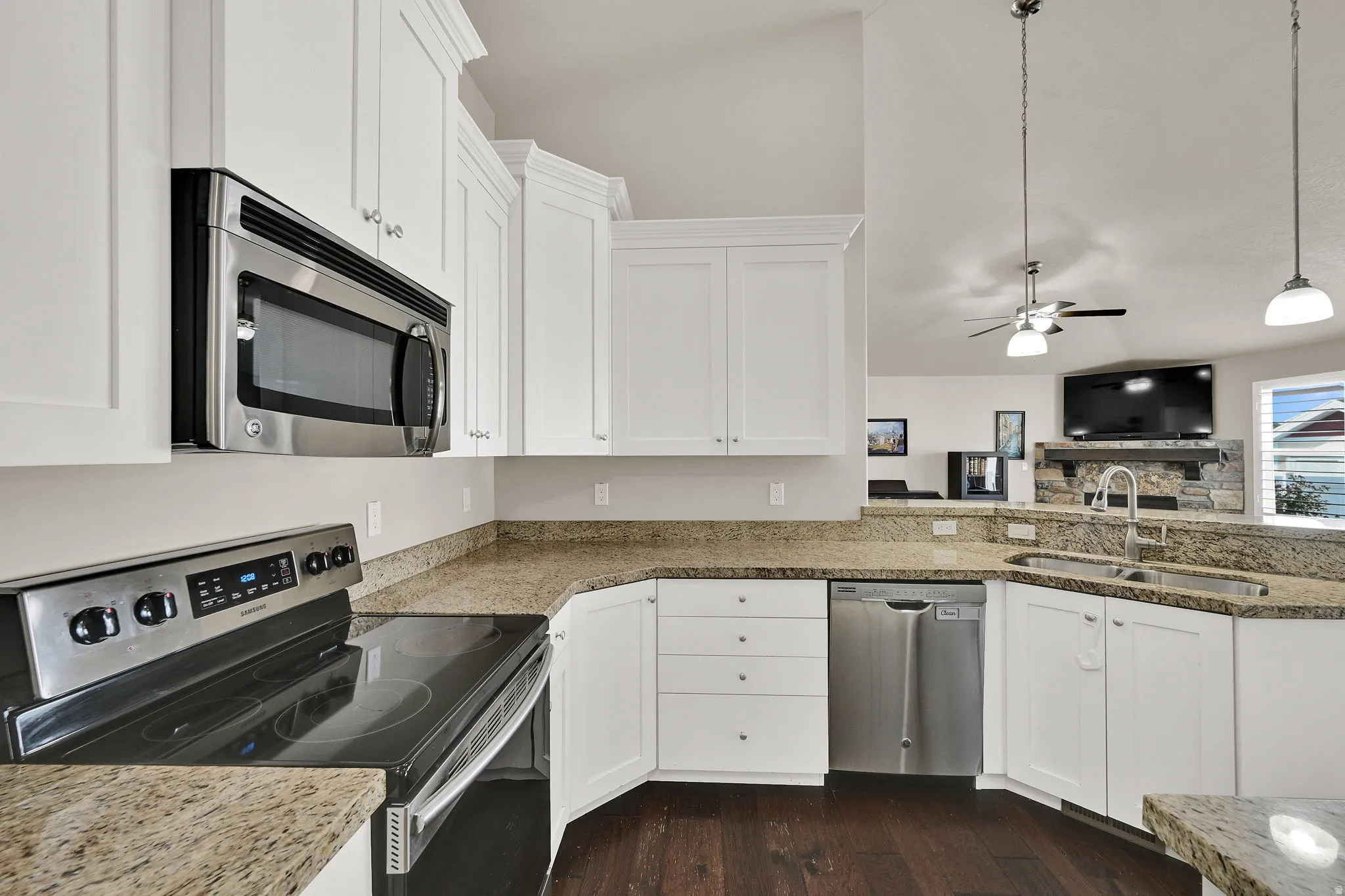 Kitchen featuring white shaker-style cabinetry, stainless steel appliances, granite countertops, and wood-finish flooring