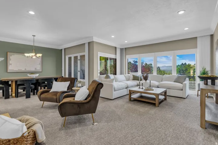 Spacious living area featuring extensive windows with landscape views, recessed lighting, crown molding, and light-toned carpet flooring