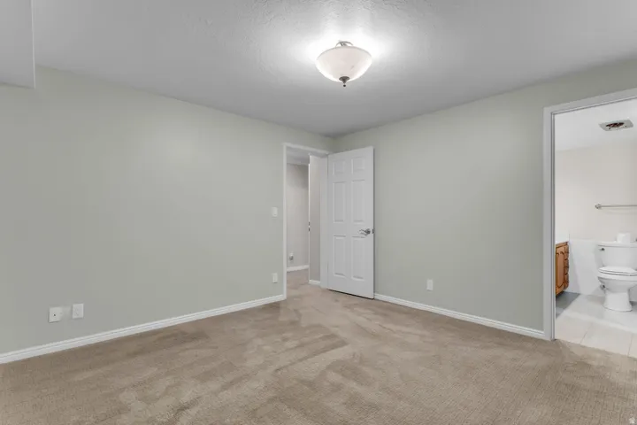 Carpeted room featuring light-colored walls, white baseboards, and a semi-flush mount ceiling light fixture