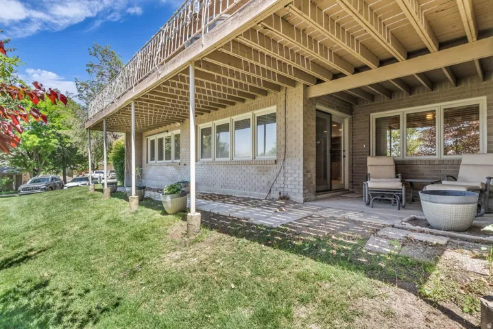 Lower-level patio featuring light brick exterior, a sliding glass door, and multiple windows