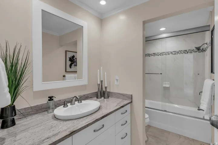 Bathroom featuring a white vanity with an oval vessel sink, brushed nickel faucet, and a light-toned stone countertop