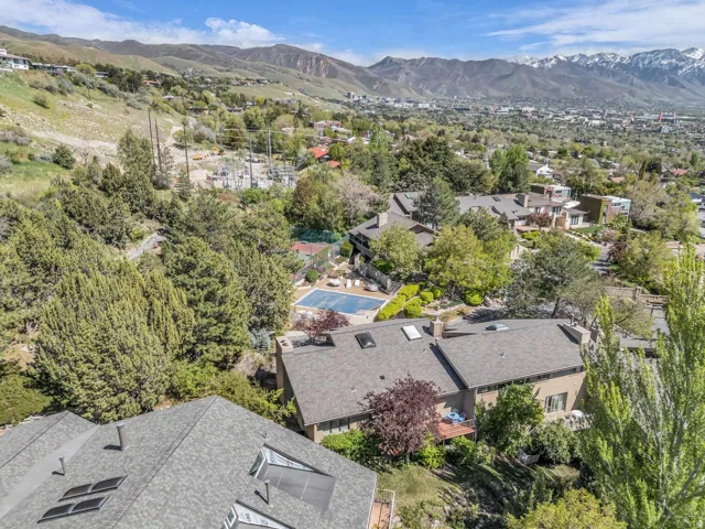 Expansive aerial perspective showcasing a residential area with mature trees and mountain backdrops