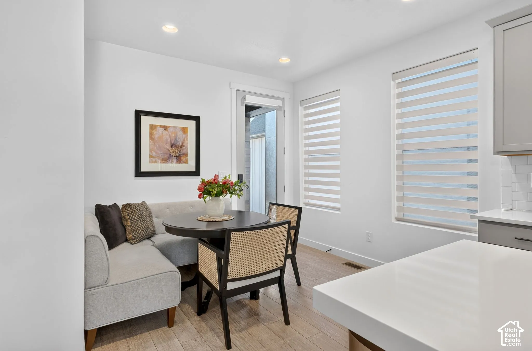 Bright dining nook featuring light wood-finish flooring, recessed lighting, and dual windows with privacy blinds