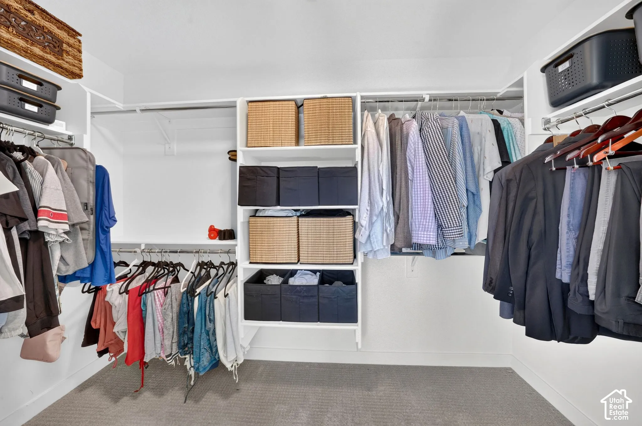 Walk-in closet featuring built-in shelving, multiple hanging rods, white walls, and gray carpet flooring