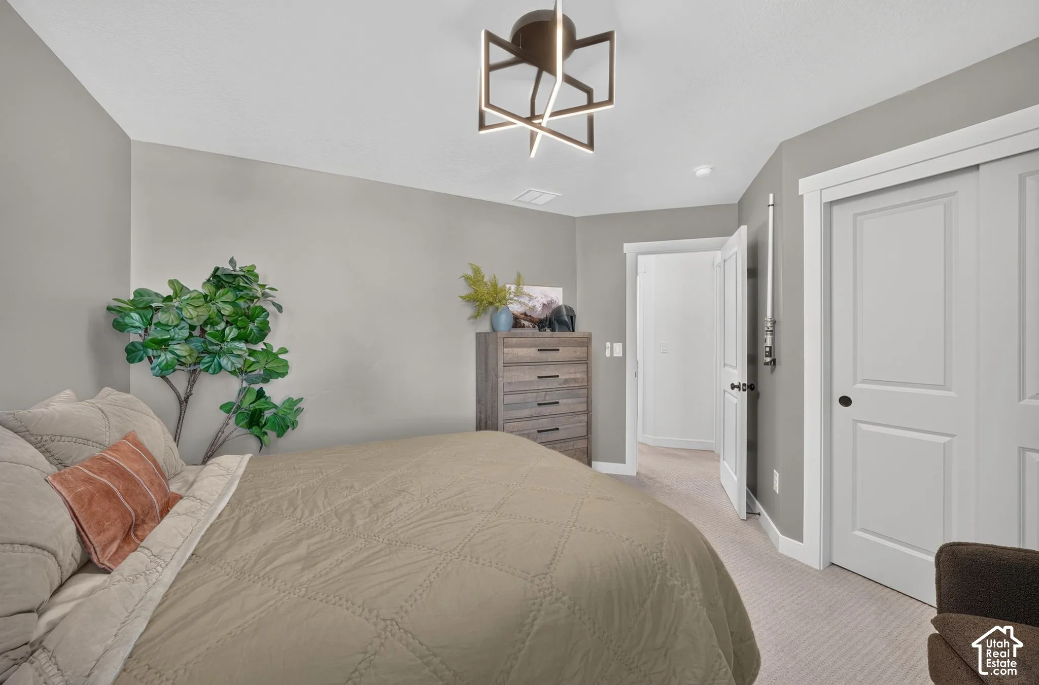 Neutral-toned room featuring a modern geometric ceiling light fixture, light gray walls, and light-colored carpet