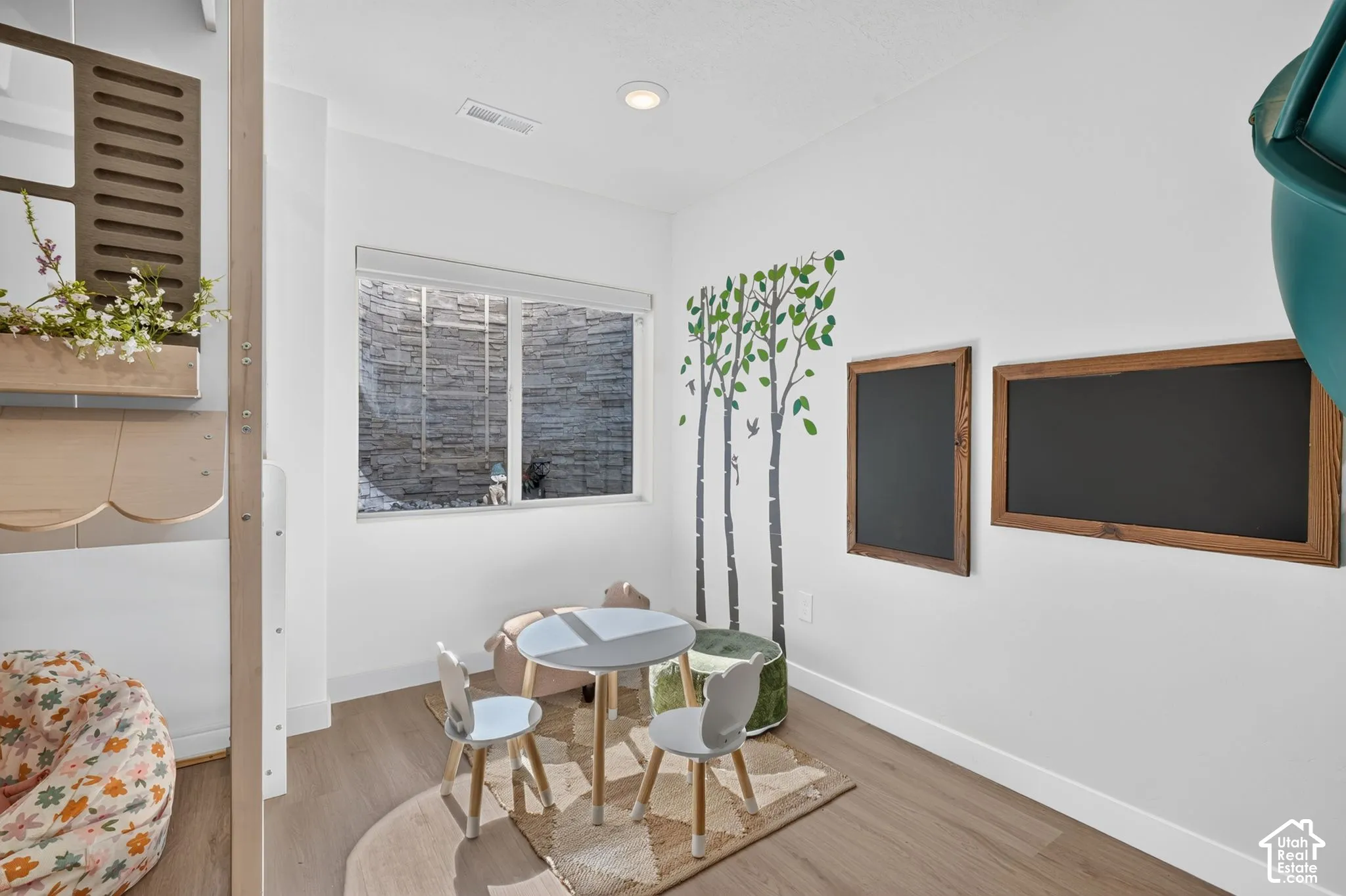 Recessed lighting illuminates this bright space featuring wood-finish flooring, white baseboards, and a window with a stone-clad exterior visible