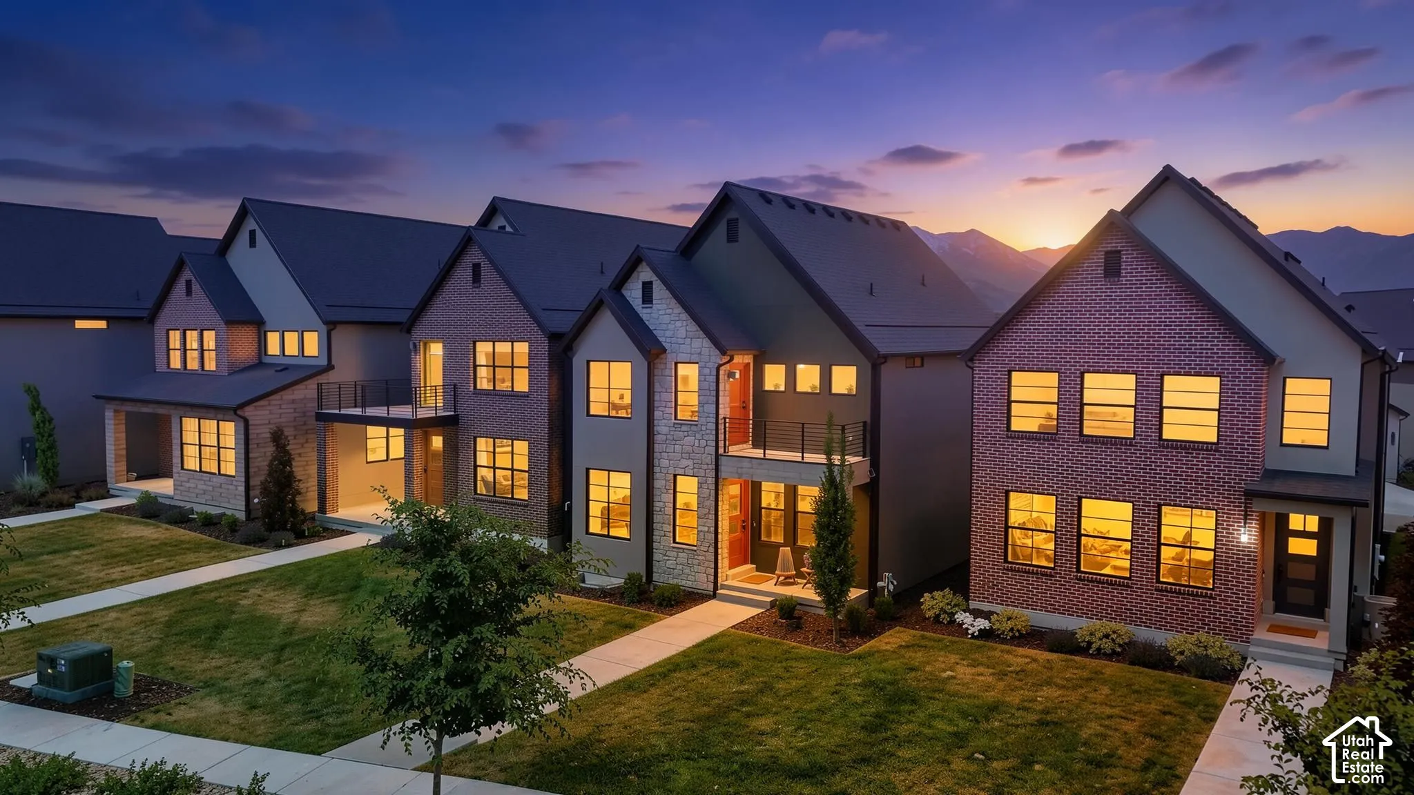 Modern row of residences featuring brick and stone facades, contrasting dark siding, and gabled roofs