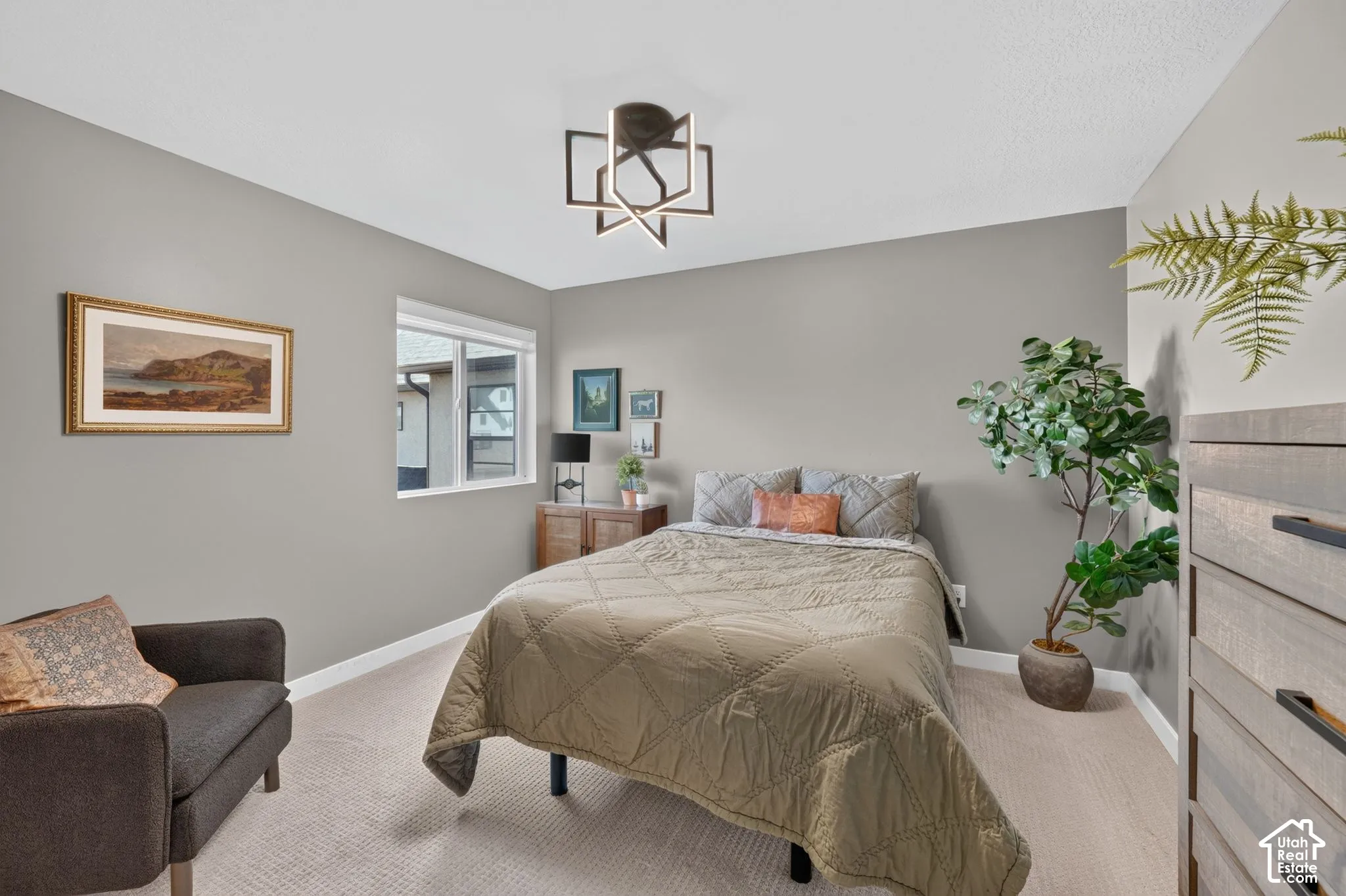 Inviting room featuring neutral wall tones, a modern geometric ceiling light fixture, and plush carpet flooring