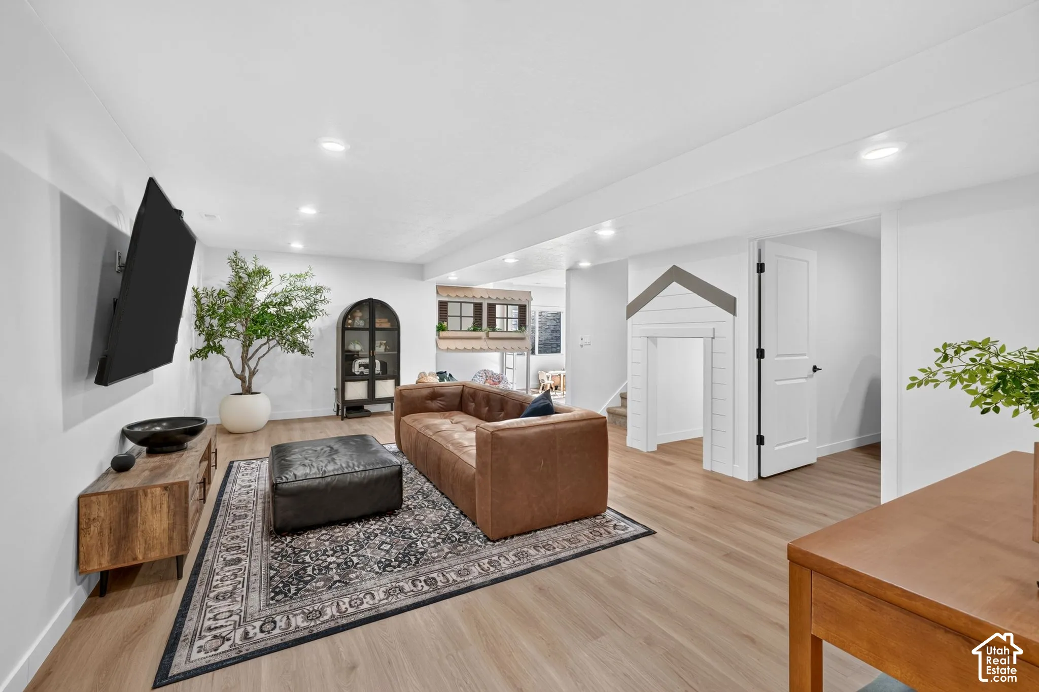 Spacious living area featuring light wood-finish flooring and recessed ceiling lighting