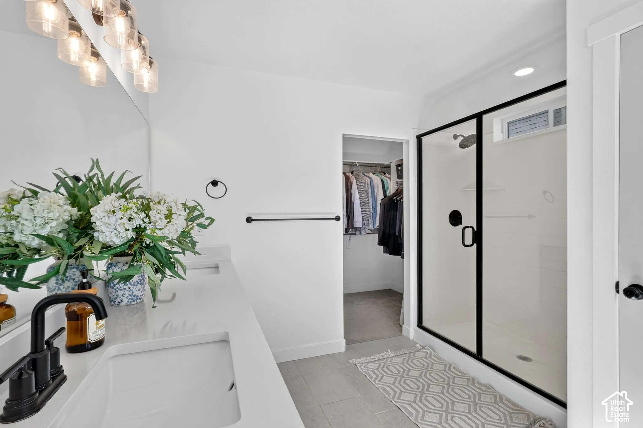 Bathroom featuring a double vanity with white countertops and integrated sinks, matte black faucets, and a large mirror