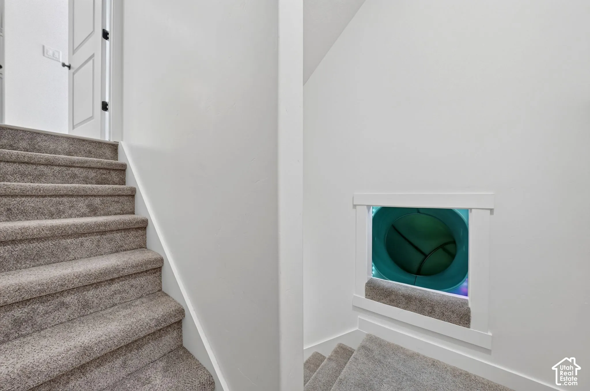 Carpeted staircase featuring a built-in play tunnel with a white trim surround