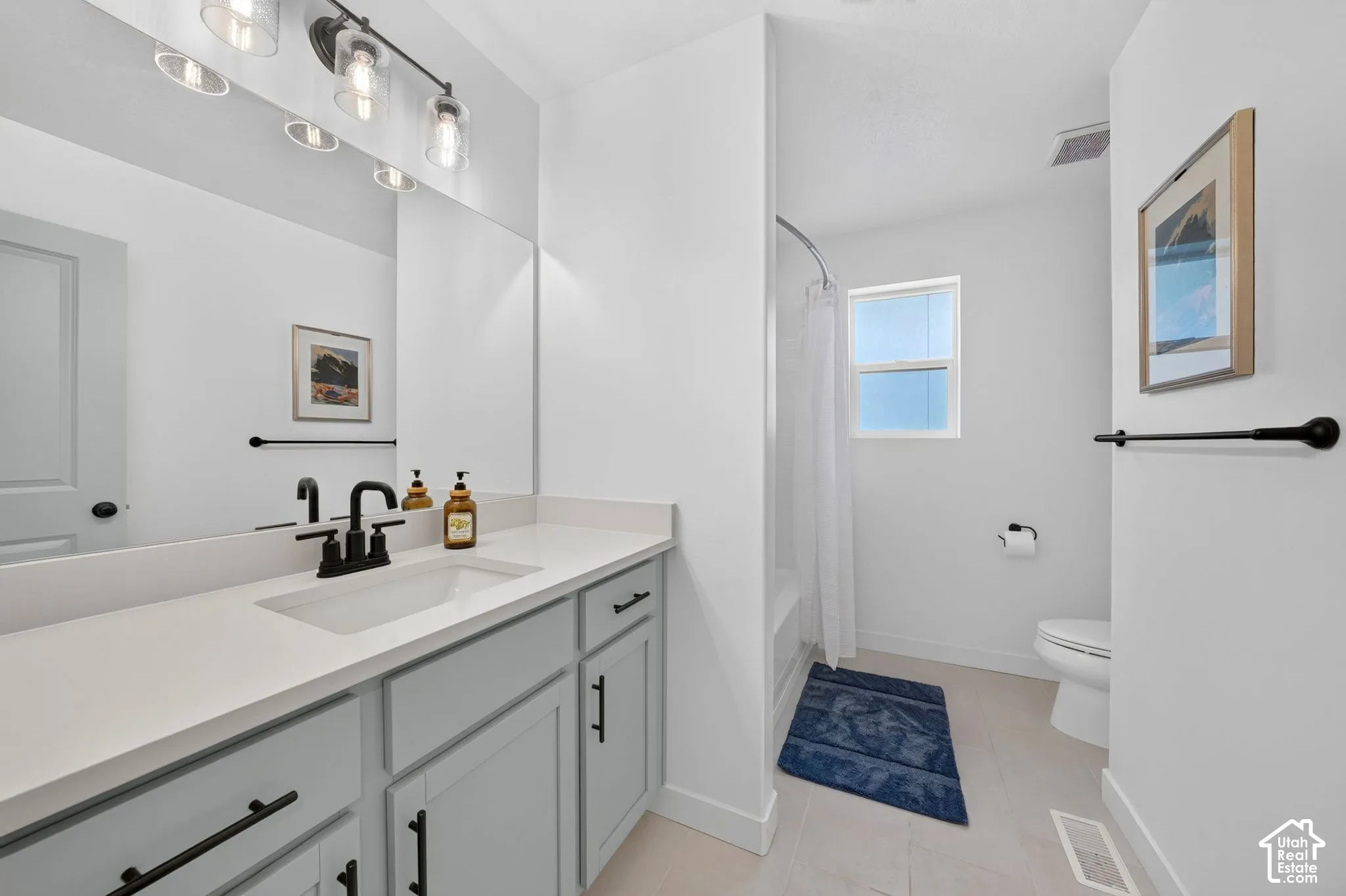 Bathroom featuring a single vanity with light grey cabinetry, white countertop, and matte black faucet