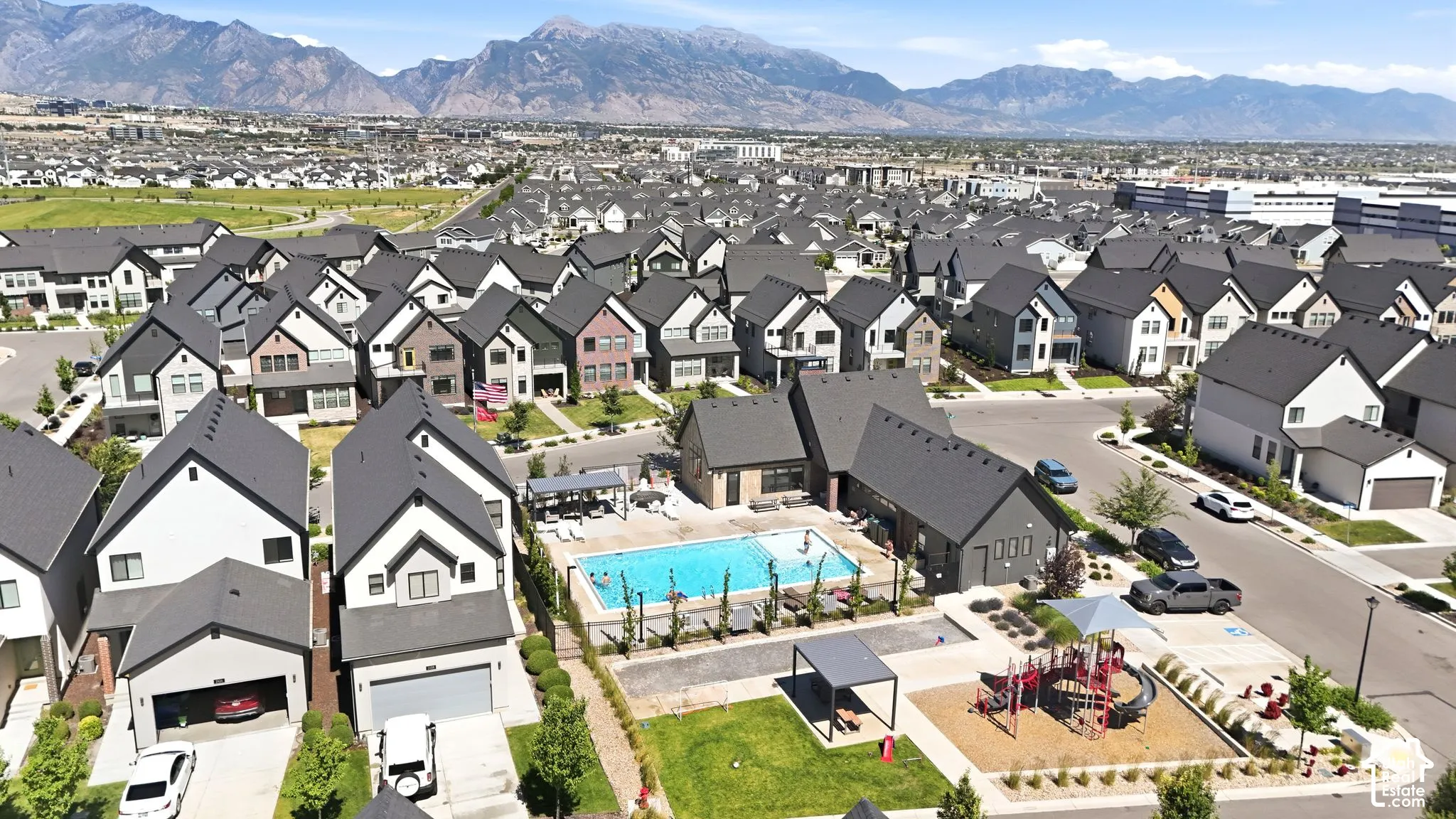 Aerial perspective showcasing a residential community with a central outdoor swimming pool, recreation area, and playground