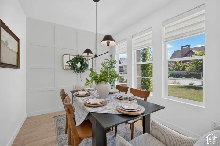Dining space featuring a decorative accent wall, wood-finish flooring, and a multi-light chandelier