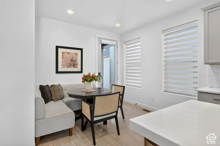 Bright dining nook featuring light wood-finish flooring, recessed lighting, and dual windows with privacy blinds