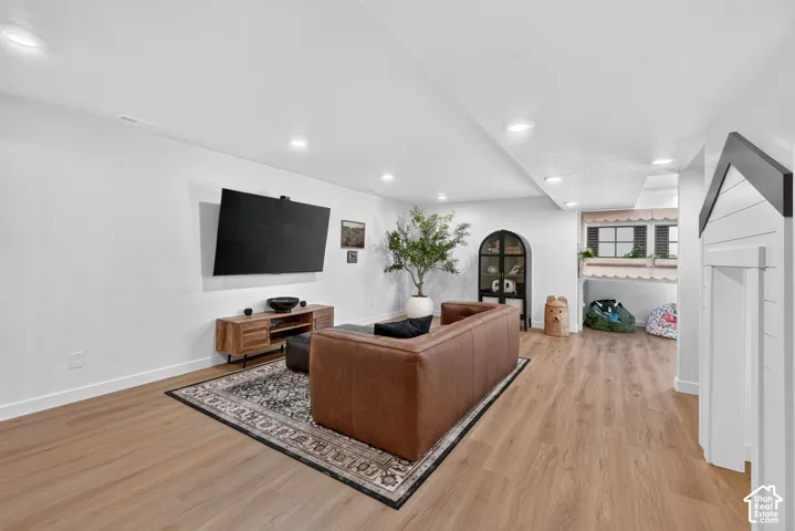 Spacious recreation room featuring wood-finish flooring, recessed lighting, and white walls