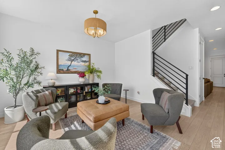 Open-concept living space featuring wood-finish flooring, a contemporary black metal stair railing, and a drum-style ceiling light fixture