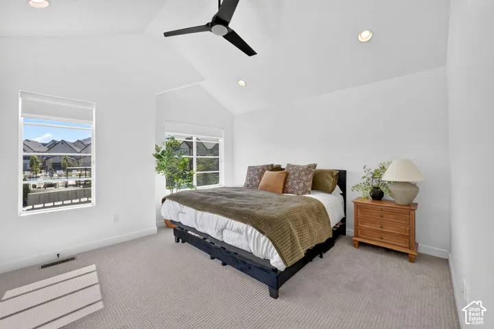 Vaulted ceilings with recessed lighting and a ceiling fan, carpeted flooring, and multiple windows with roller shades