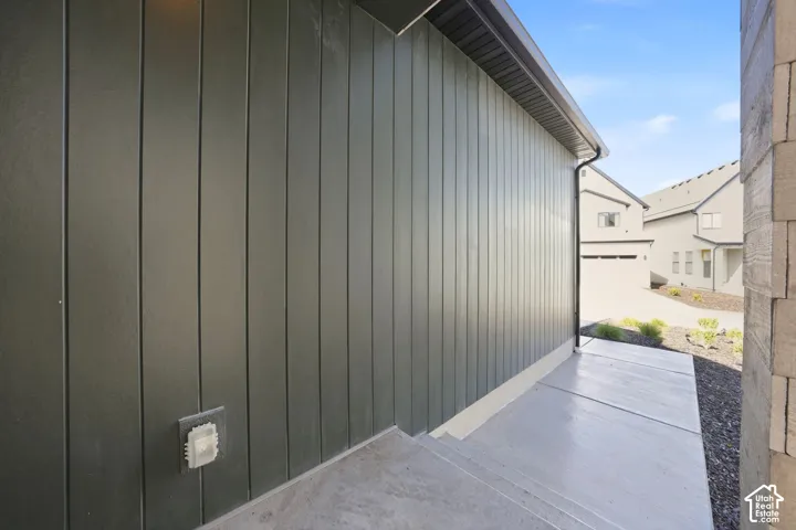 Vertical panel siding in a dark finish, concrete steps, and a concrete walkway