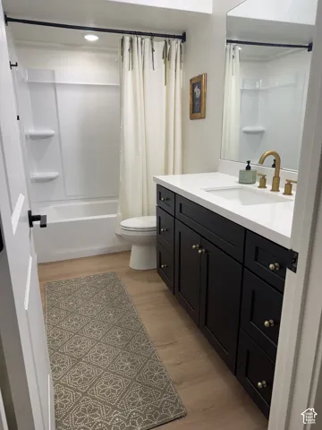 Bathroom featuring a full vanity with a white countertop, an undermount sink, and black cabinetry with brass-tone hardware