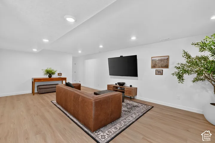 Spacious entertainment room featuring recessed lighting, light wood-finish flooring, and white baseboards