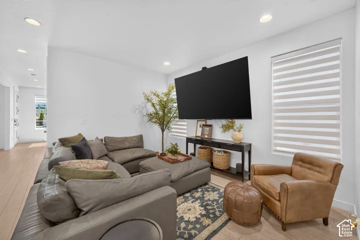 Open-concept living space featuring wood-finish flooring, recessed lighting, and a window with layered shades
