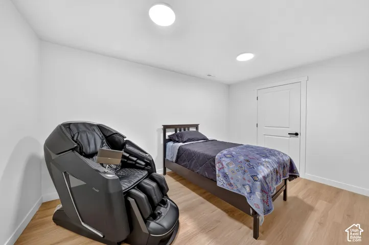 Bedroom featuring light wood-finish flooring, white walls, and two recessed ceiling lights