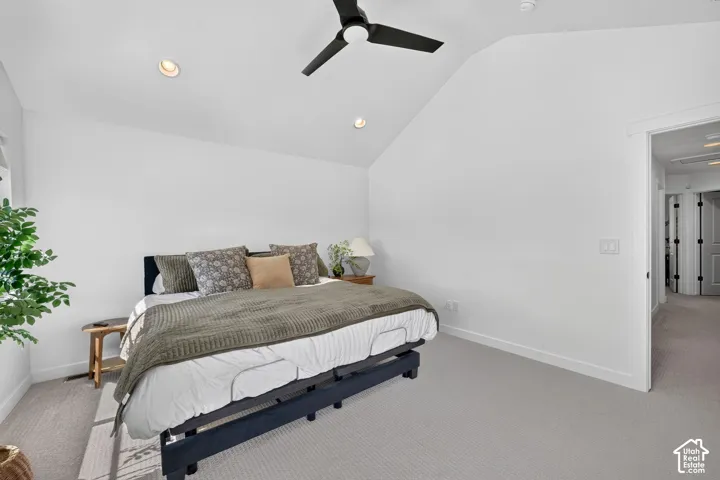 Carpeted bedroom featuring a vaulted ceiling with a ceiling fan, recessed lighting, and a white baseboard trim