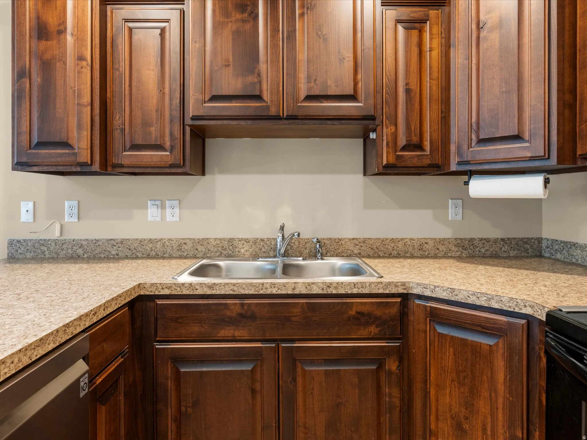 Kitchen featuring a stainless steel double basin sink, and dark wood-finish cabinetry.