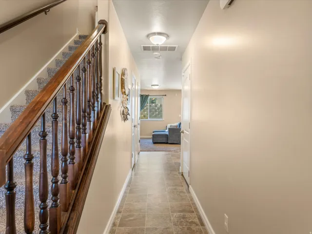 Entry featuring tiled flooring, neutral wall tones, and a wood-finish staircase with carpeted treads