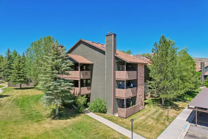 Multi-level building with dark green siding and a brown roof