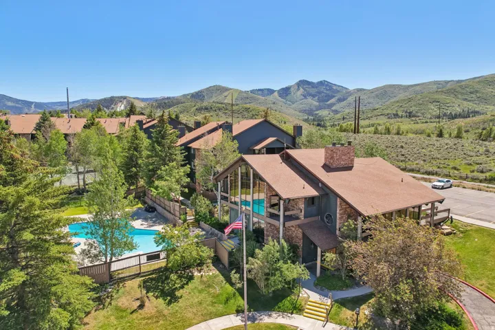 Stone-clad exterior with a prominent chimney, large windows, and an expansive mountain backdrop