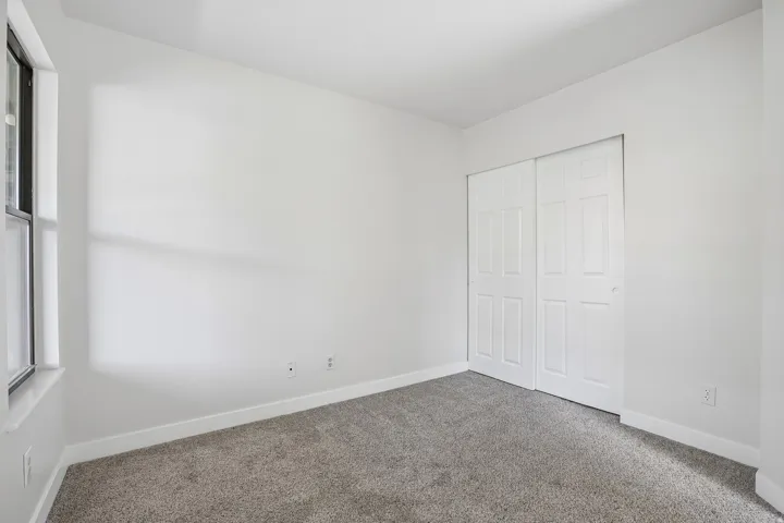 Room featuring plush gray carpet, white painted walls, white baseboards, and a window with a white sill