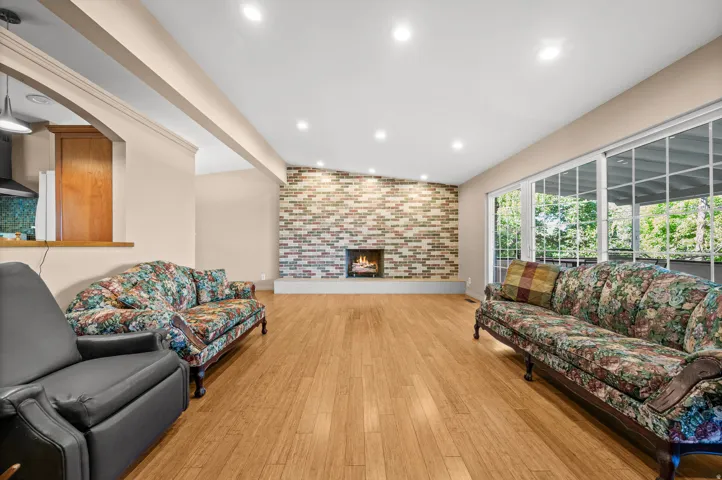 Spacious living area featuring wood-finish flooring, a contemporary fireplace with a brick surround, and large sliding glass doors