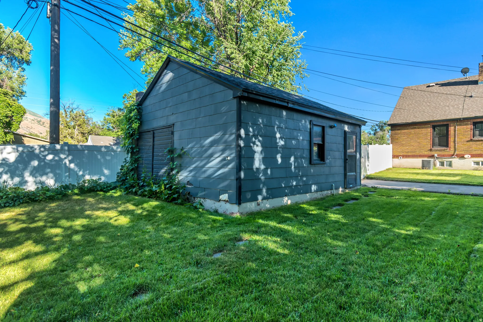 Back of garage with man door entrance.  Deep grass backyard, going further back beyond this picture