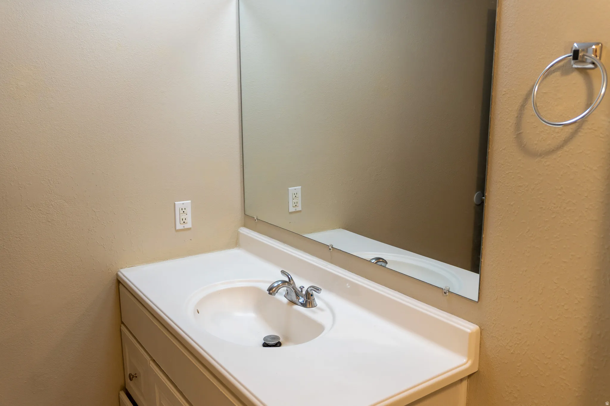 White vanity with integrated sink, chrome faucet, and expansive wall mirror