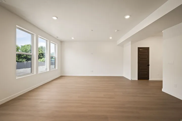 Spacious interior with wood-finish flooring, recessed lighting, and a dark paneled door