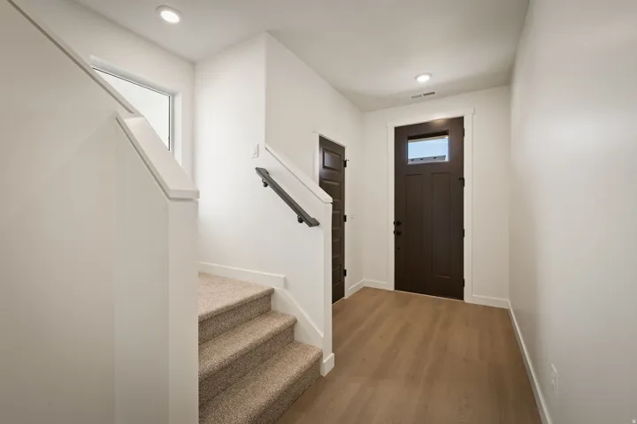 Entryway featuring a dark wood-finish front door with an upper window pane, wood-finish flooring, recessed lighting, and a neutral color palette