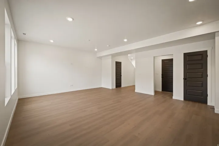 Spacious room featuring wood-finish flooring, recessed lighting, and multiple windows