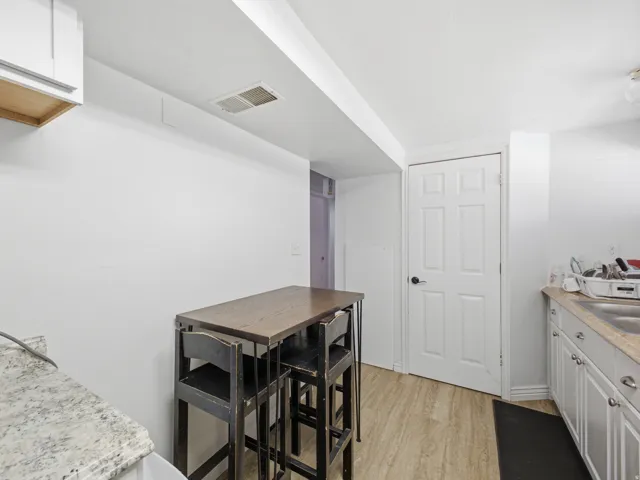 Kitchen area featuring white cabinetry, light-toned wood-finish flooring, a stainless steel sink, and a light-colored countertop