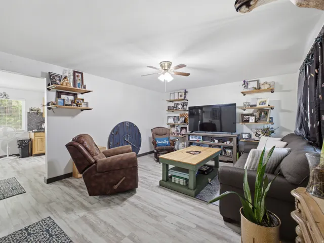 Living area featuring wood-finish flooring, a ceiling fan, and a wall-mounted entertainment center