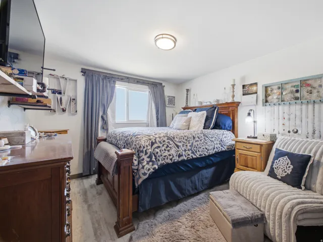 Spacious room with light wood-finish flooring, a ceiling-mounted light fixture, and a large window with blue curtains