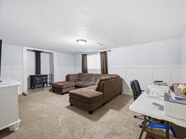 Spacious room featuring neutral carpeting, white wainscoting, and a ceiling-mounted light fixture