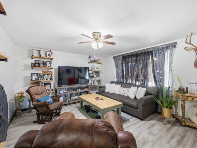 Living area featuring light wood-finish flooring and a ceiling fan