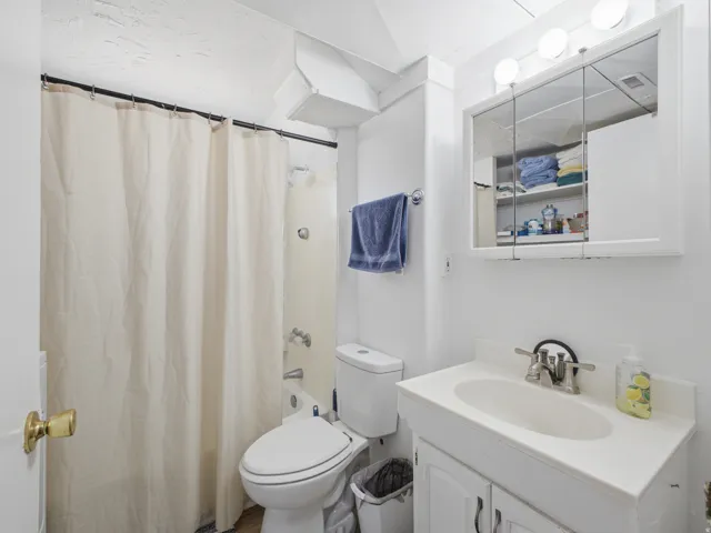 Bathroom featuring a white vanity with integrated sink, chrome faucet, and a wall-mounted mirrored medicine cabinet with vanity lighting