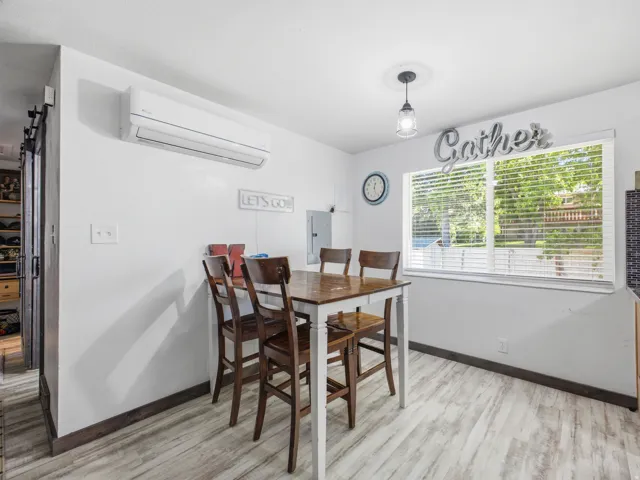 Living space featuring light wood-finish flooring, white walls, and a large window with horizontal blinds