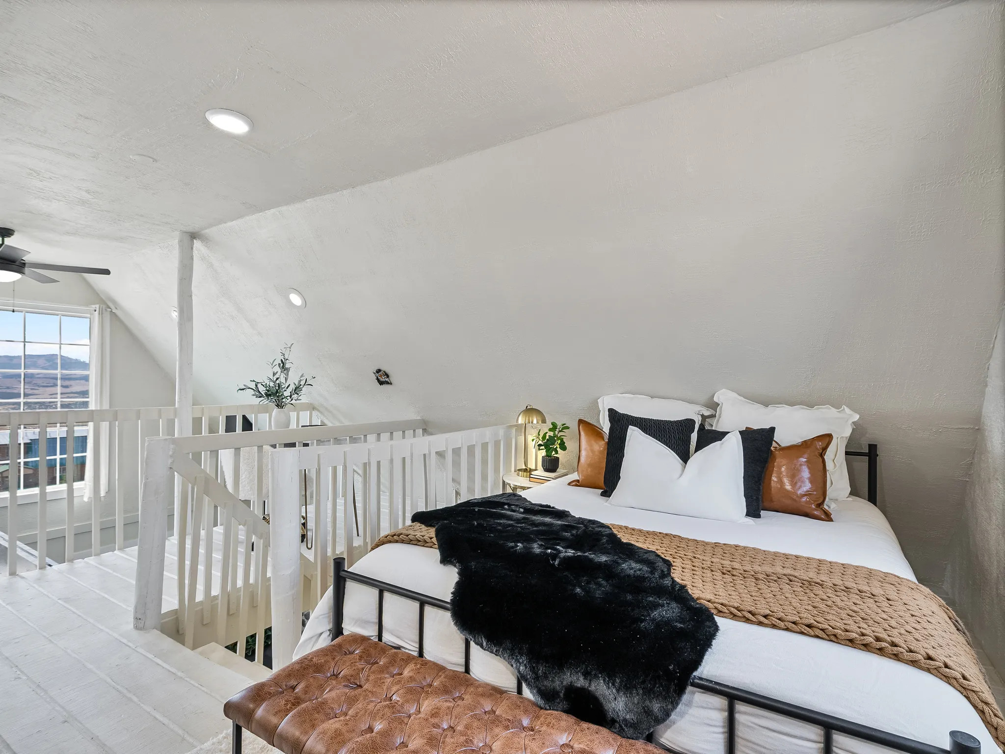 Loft bedroom featuring vaulted ceiling, recessed lighting, and a window overlooking distant scenery