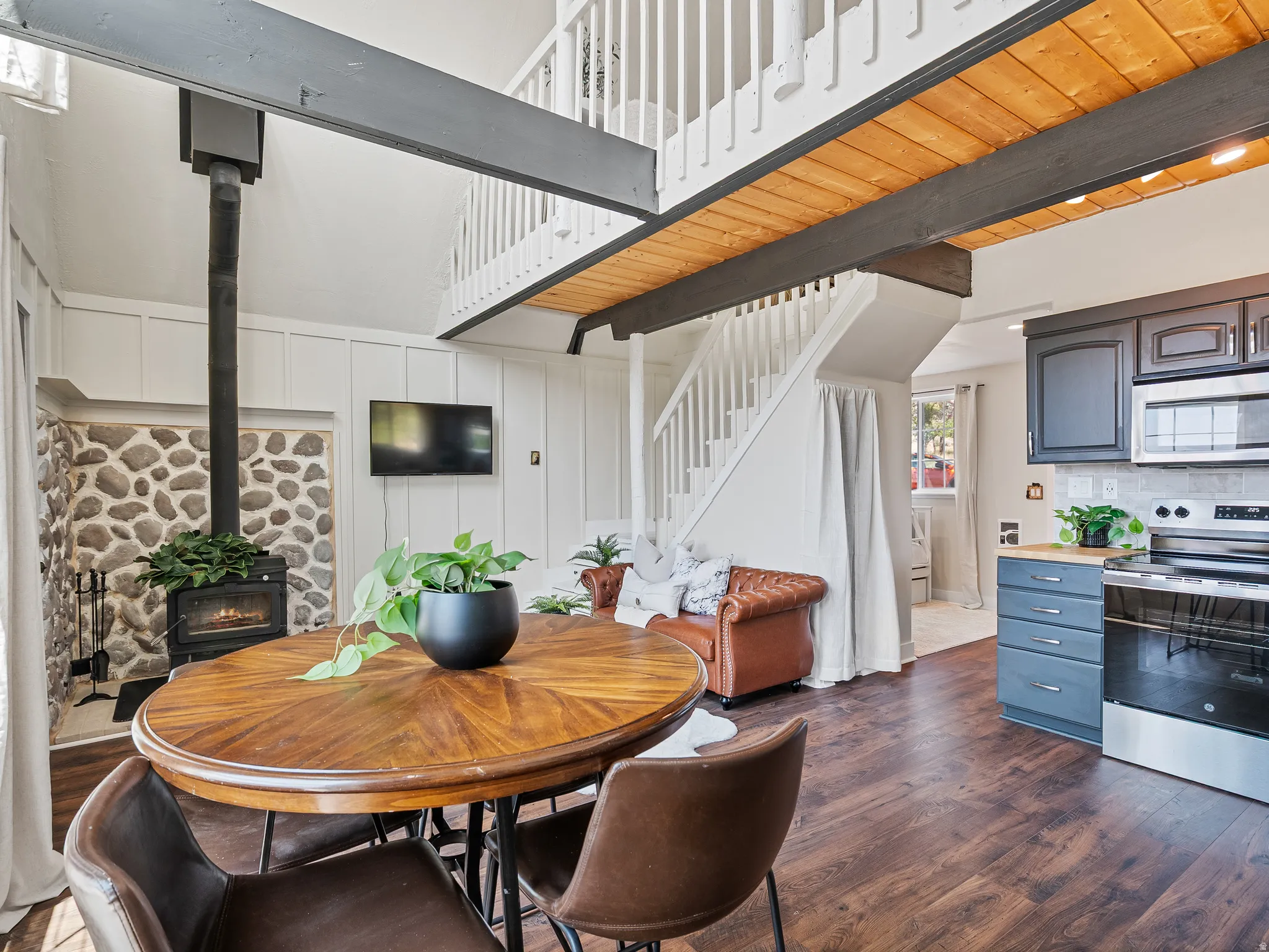 Open-concept living area featuring, new flooring, a stone-faced wood-burning stove, and a white paneled accent wall