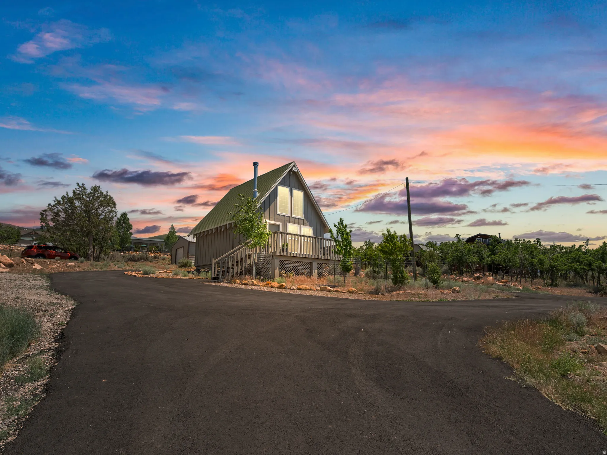 Sunset cabin with asphalt driveway.