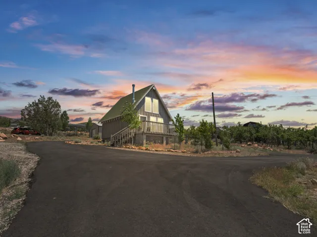 Sunset cabin with asphalt driveway.